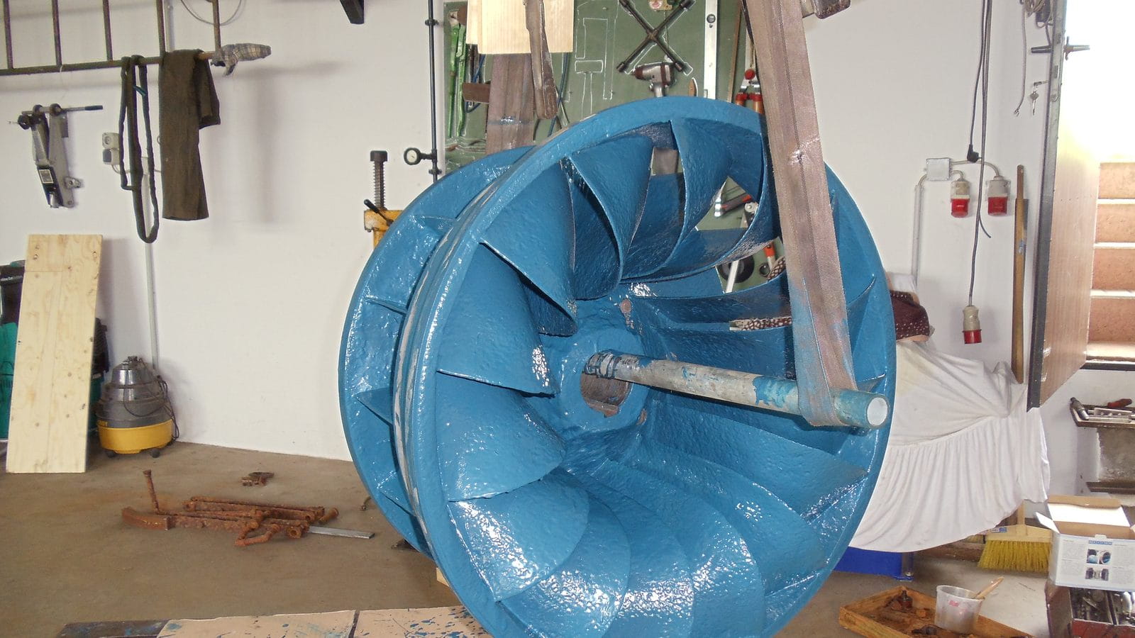 Mit blauer Keramik-Epoxidbeschichtung instand gesetztes Pumpenlaufrad hängt in einer Werkstatt