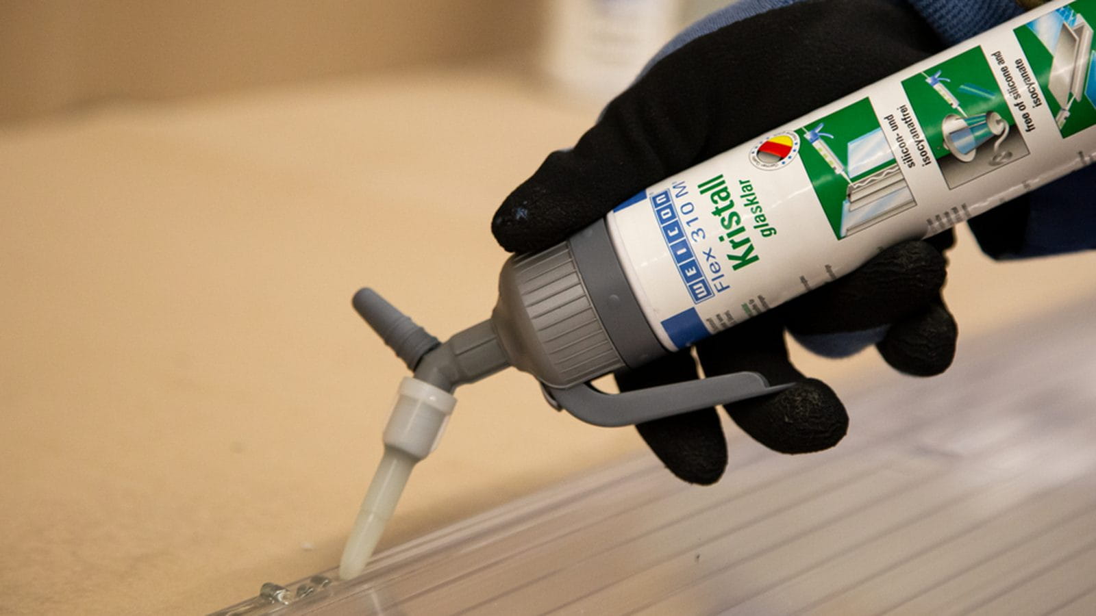 Transparenter MS-Polymer-Klebstoff wird aus dem Schlauchbeutel als Raupe auf eine Platte gezogen